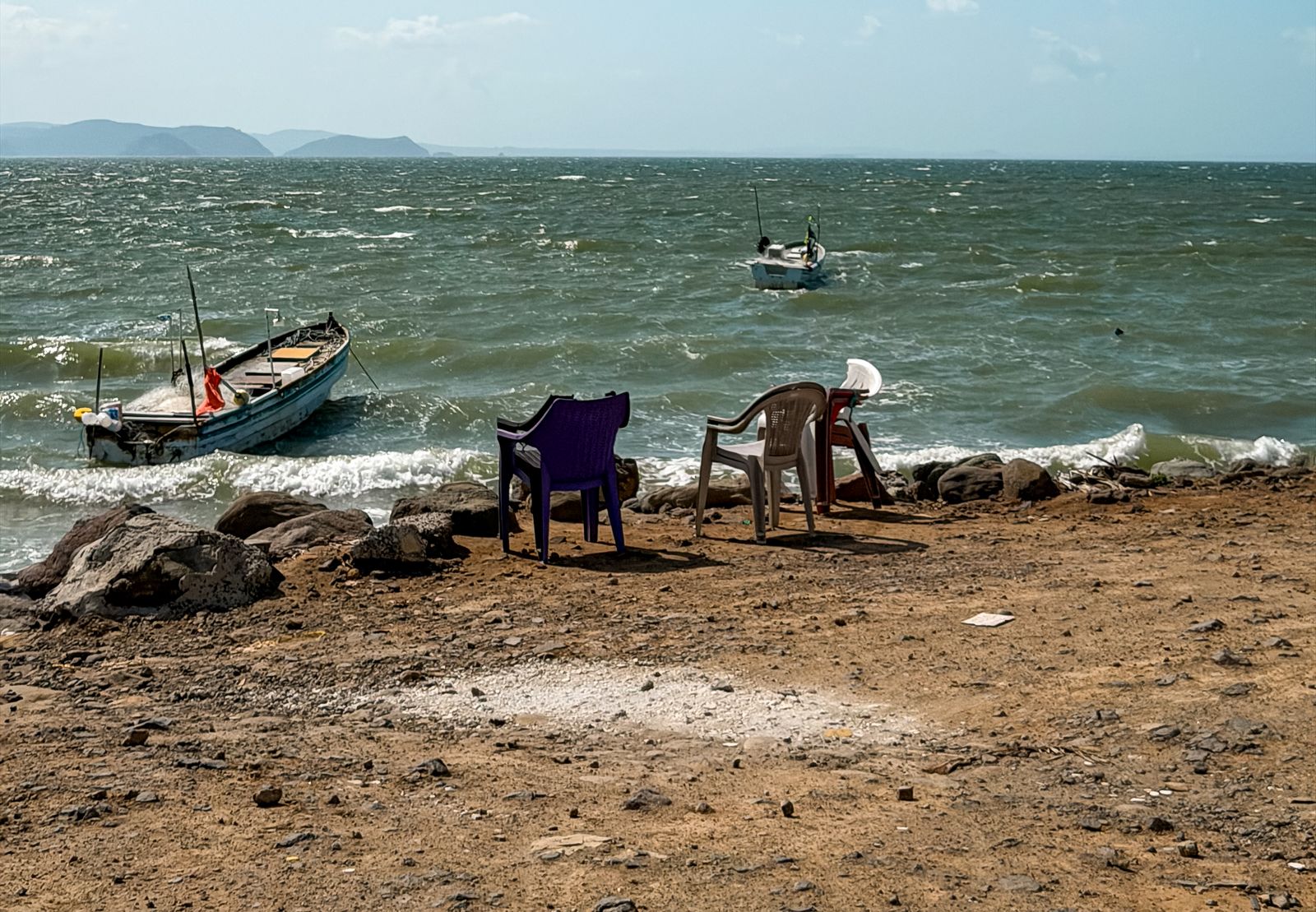 Fishing boats and beach chairs facing the water